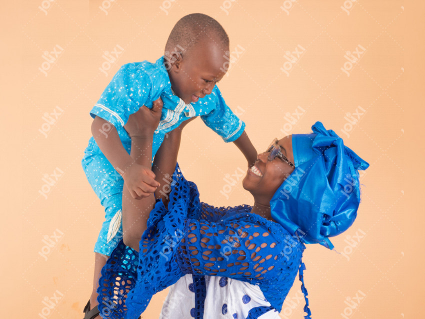 Une maman africaine contente jouant avec son bébé sur un fond beige