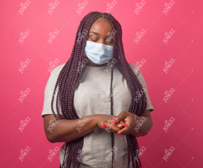 Jeune femme africaine portant un cache nez nettoyant ses mains sur un fond  rose - Photo #4951 - Jolixi