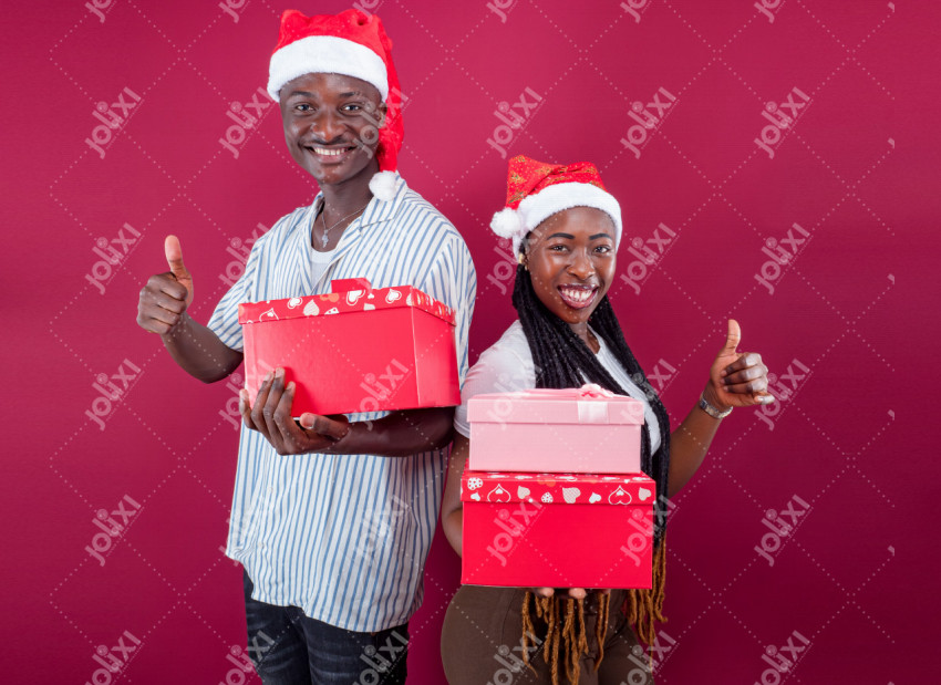 Homme et femme africain dos à dos et portant des cadeaux de Noël debout sur  fond rouge - Photo #6707 - Jolixi