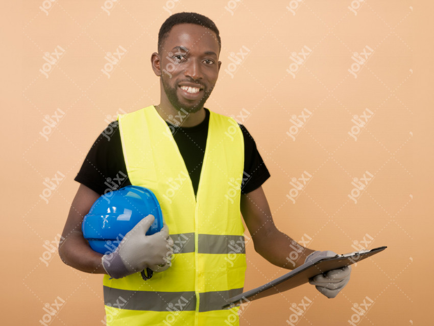 Un homme africain en tenue de chantier attrapant son casque casque bleu et  un porte-bloc à pince - Photo #2305 - Jolixi