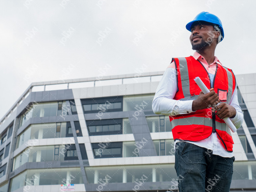 Chef d'entreprise africain en tenue de chantier tenant un plan de travail à  l'extérieur - Photo #6291 - Jolixi